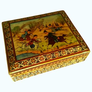 May include: A square, decorative box with a detailed painting on the lid depicting a polo match. The box has a gold-colored border with intricate floral and geometric patterns. The painting features figures on horseback in a landscape setting.