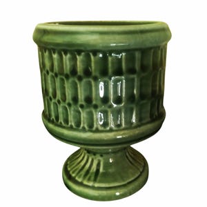 Può includere: Un vaso di ceramica verde con base a piedistallo. Il vaso presenta un motivo strutturato e ripetitivo attorno al corpo e una finitura lucida. Adatto per uso interno o esterno.