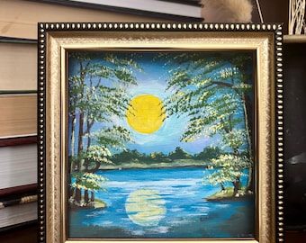 May include: Framed painting of a moonlit lake scene. The artwork features a large yellow sun, blue water, and trees with white and green foliage. The frame is gold and black, and the painting measures 10x10 cm.