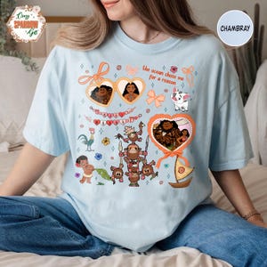 Może przedstawiać: Jasnoniebieska koszulka z kolorową grafiką przedstawiającą postacie i tekst z popularnego filmu animowanego. Projekt zawiera ramki w kształcie serca, kokardy i frazę "the ocean chose me for a reason."