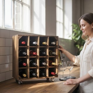 以下が含まれることがあります： 木製のワインラックには、さまざまなワインボトルを収納できる複数のコンパートメントがあります。 ラックは車輪付きで、木製のカウンタートップに置かれています。 人が2つのワイングラスの近くでワインボトルを持っています。 テキスト「Crafted for Moments. Your Wine, Elevated。」