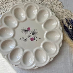 May include: A set of three ceramic mugs with a speckled, matte finish. Each mug features a different color: light blue, cream, and gray. The mugs have a simple, modern design with a rounded shape and a comfortable handle.