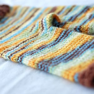 May include: Striped knitted baby leggings in brown, yellow, blue, and white.