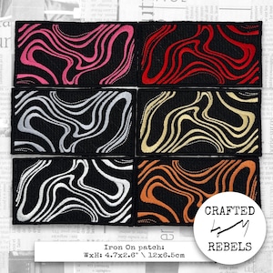 Puede incluir: Seis parches termoadhesivos con fondo negro y diseño ondulado en varios colores: rosa, rojo, plateado, dorado, blanco y naranja. Cada parche mide 12 x 6,5 cm. Los parches están etiquetados como "Iron On patch" y "Crafted by Rebels."