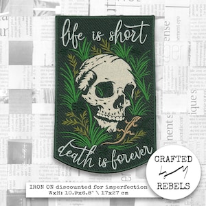 Puede incluir: Parche termoadhesivo verde oscuro con el texto "life is short" y "death is forever". El parche presenta una calavera, un lagarto y follaje verde. El parche mide 27 x 17 cm.