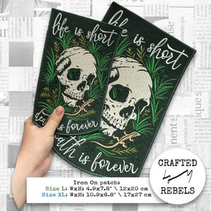May include: Two dark green iron-on patches with the text "life is short, death is forever". Each patch features a skull design with a lizard and plant illustrations. Size L: 12x20 cm, Size XL: 17x27 cm.