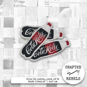 May include: Embroidered iron-on patches in the shape of a soda bottle, with the words "Cola Holic" in red script on a black background. The patches are white around the edges and measure 0.9 x 2.8 inches.