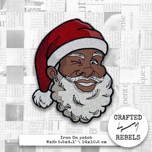 May include: Embroidered iron-on patch featuring a smiling Santa Claus with brown skin, a white beard, and a red hat. The patch measures 5.5 x 4.1 inches.