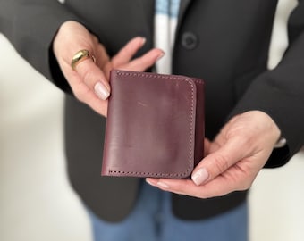 May include: A burgundy leather wallet with a stitched edge.