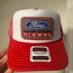 May include: A red, white, and blue Ford Trucker hat. The hat features the Ford logo and the words "POWER STROKE DIESEL." The hat has a foam front and a durable snap closure. The hat is OSFM.