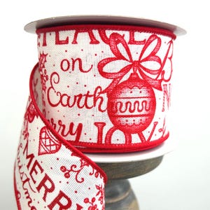 May include: A spool of white wired ribbon featuring red text and holiday graphics. The print includes the words Peace on Earth, Merry, and Joy, alongside illustrations of a Christmas ornament, holly leaves, and berries with red stitched edges.