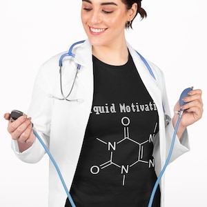 以下が含まれることがあります： 「Liquid Motivation」の文字と白いカフェイン分子図が描かれた黒いTシャツ。白い白衣を着て聴診器を持っている人。