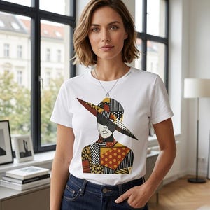 May include: A white t-shirt featuring a graphic of a woman wearing a wide-brimmed hat and sunglasses. The hat and upper body are composed of patchwork patterns in black, yellow, and brown. The woman is wearing a silver necklace and blue jeans.