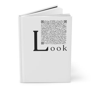 以下が含まれることがあります： 白いハードカバーの本で、表紙に黒で「Look」という文字が印刷されています。「L」の文字は大きく、QRコードが付いています。本は少し開いており、白いページが見えています。