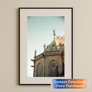 May include: A black and white photograph of a stone building with a pointed roof and intricate details. The building is framed by a black picture frame.