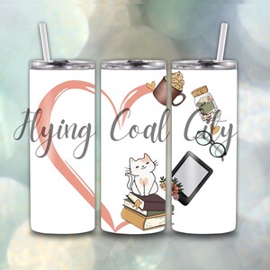 May include: A white tumbler with a straw featuring a pink heart and the text "Flying Coal City." The design includes a cat on books, a coffee cup, a jar, glasses, and an e-reader, all in a whimsical style.