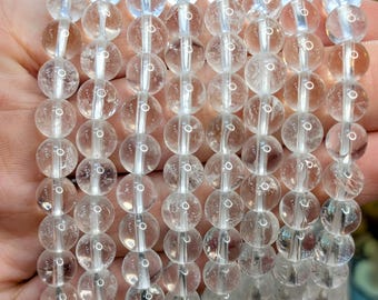 May include: A stack of clear quartz crystal bracelets. Each bracelet is made of round beads and has a simple design.