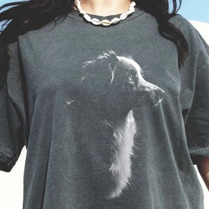 May include: A dark gray oversized t-shirt with a black and white image of a dog's head on the front. The text "PEPPER" is visible in the lower left corner of the image.