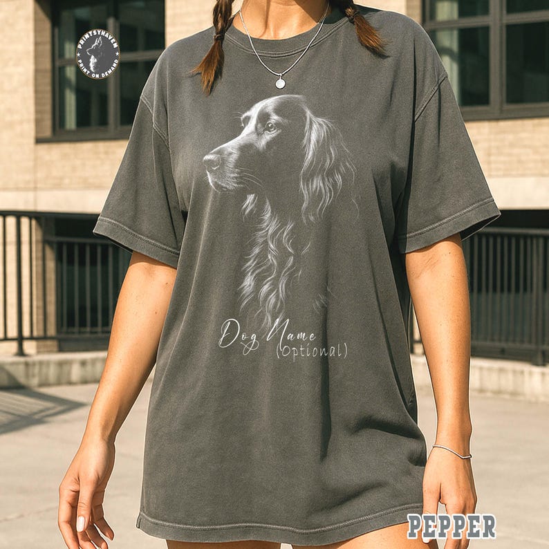 May include: Dark gray t-shirt featuring a detailed illustration of a dog's head in profile. The design includes the text "Dog Name (Optional)" in a script font. The shirt has a relaxed fit and short sleeves.