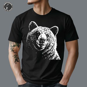 Puede incluir: Camiseta negra con un gr&aacute;fico blanco de la cara de un oso. La ilustraci&oacute;n del oso es detallada, mostrando la textura del pelaje y los rasgos faciales. La camiseta tiene mangas cortas y cuello redondo. El logotipo de Printshaven es visible en la esquina superior izquierda.