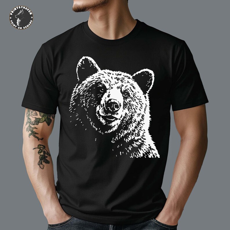 Puede incluir: Camiseta negra con un gr&aacute;fico blanco de la cara de un oso. La ilustraci&oacute;n del oso es detallada, mostrando la textura del pelaje y los rasgos faciales. La camiseta tiene mangas cortas y cuello redondo. El logotipo de Printshaven es visible en la esquina superior izquierda.