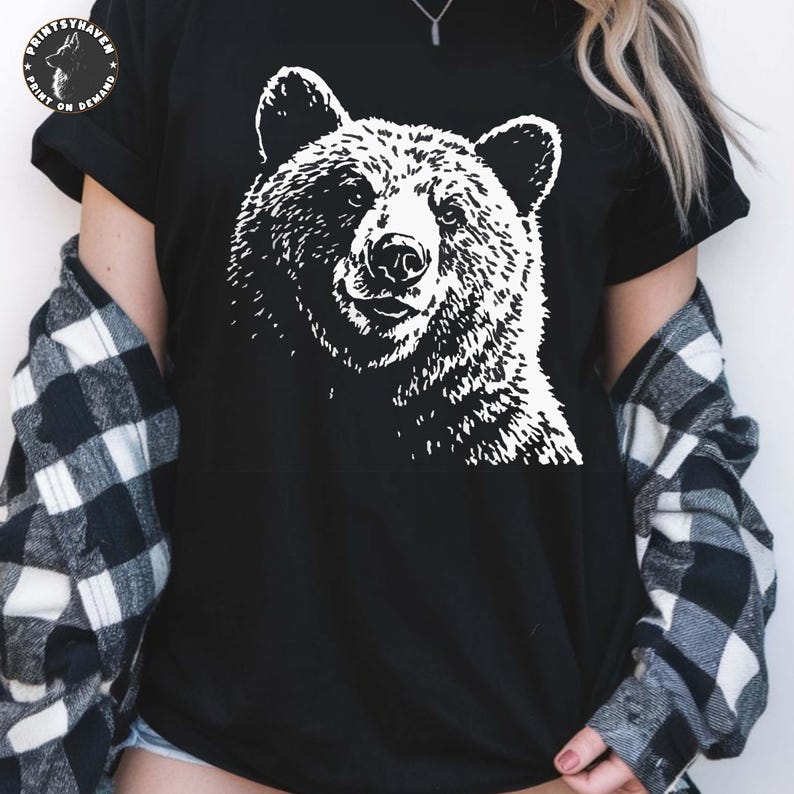 Puede incluir: Camiseta negra con un gr&aacute;fico blanco de la cara de un oso. El pelaje del oso est&aacute; detallado y el dise&ntilde;o est&aacute; centrado. La camiseta tiene mangas cortas y cuello redondo. El logotipo de la marca es visible en la parte superior izquierda.