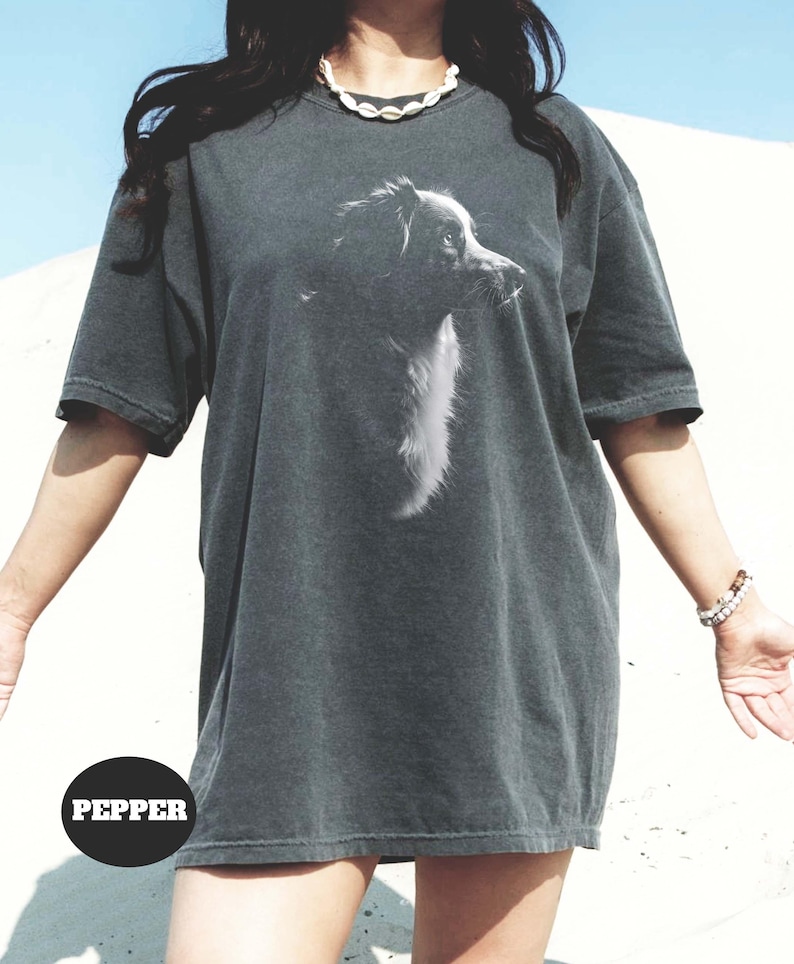 May include: A dark gray oversized t-shirt with a black and white image of a dog's head on the front. The text "PEPPER" is visible in the lower left corner of the image.