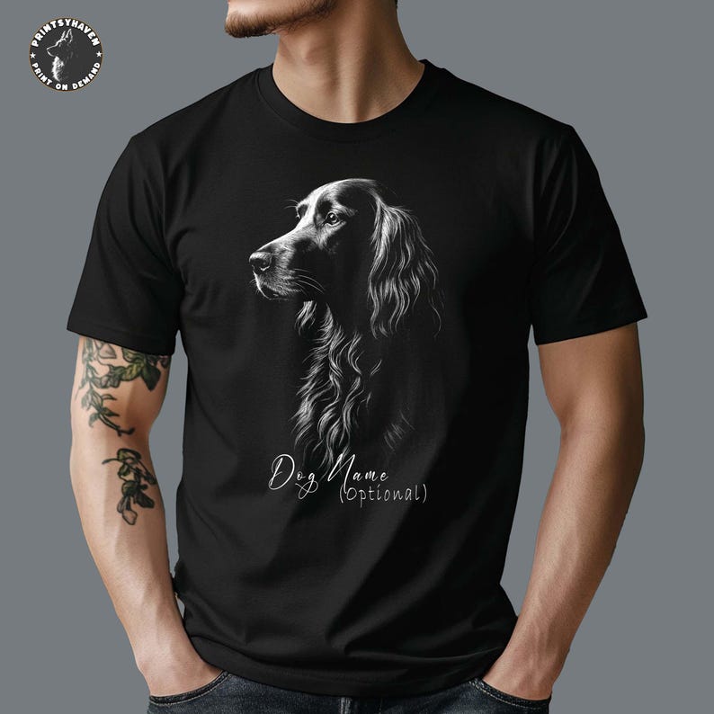 May include: Black t-shirt featuring a detailed, grayscale illustration of a dog's profile. The dog has long, flowing fur. The text "Dog Name (Optional)" is below the image. The shirt has a crew neck and short sleeves.