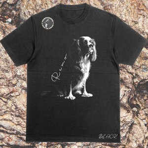 May include: Black t-shirt with a white graphic of a Cavalier King Charles Spaniel dog. The dog is looking to the right and the text "Remo" is written in cursive above the dog. The text "BLACK" is printed in white at the bottom of the shirt.