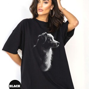 May include: Black oversized t-shirt featuring a black and white silhouette of a dog's head. The dog is looking to the right. The t-shirt has a crew neck and short sleeves.