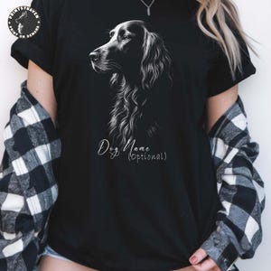May include: Black t-shirt featuring a detailed white illustration of a dog's head and neck. The text "Dog Name (Optional)" is written in a cursive font below the illustration. The shirt has short sleeves.