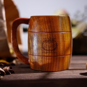 Könnte beinhalten: Ein Bierkrug aus Holz mit einem dunkelbraunen Griff und Körper. Der Krug hat ein geätztes Emblem mit dem Text "THE SMITH FAMILY". Der Krug ist aus Holz und hat eine natürliche Holzmaserung. Traditioneller Stil.