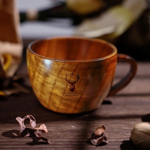 Könnte beinhalten: Eine Holztasse mit Henkel, mit einem Hirschkopf-Logo und dem Wort "GROOMSMAN" darunter. Die Tasse hat eine natürliche Holzmaserung und steht auf einer Holzoberfläche.