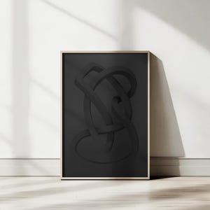 Puede incluir: Una impresión artística enmarcada con un diseño abstracto negro tridimensional de formas entrelazadas. La obra de arte está sobre un fondo oscuro y enmarcada en un marco de madera clara. La impresión está apoyada contra una pared blanca.