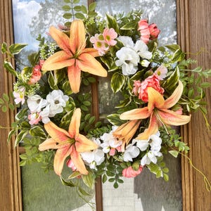 Corona de verano y otoño con lirios coral y flores artificiales blancas. Corona naranja, verde y blanca para la puerta principal.