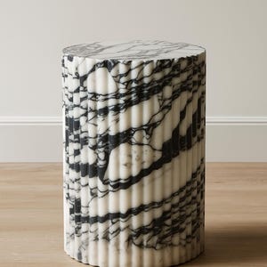 May include: A cylindrical marble side table with a fluted design. The table features a black and white veined pattern. The table is approximately 18 inches tall and 14 inches in diameter, suitable for indoor use.