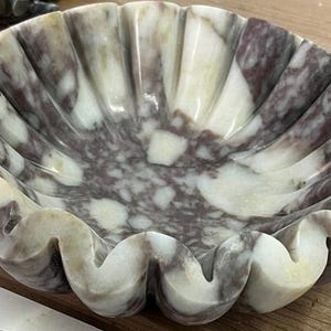 Pu&ograve; includere: Una ciotola decorativa in marmo con bordo smerlato. La ciotola presenta un mix di tonalit&agrave; bianche, grigie e viola. Il design della ciotola ricorda una conchiglia. Questa ciotola &egrave; adatta per scopi decorativi.