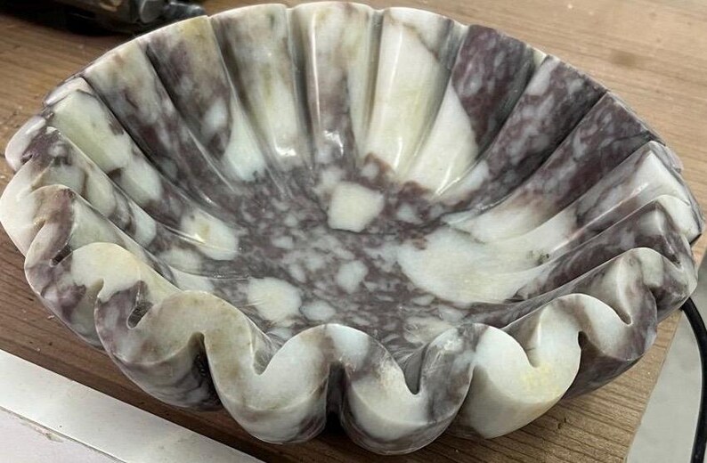 Pu&ograve; includere: Una ciotola decorativa in marmo con bordo smerlato. La ciotola presenta un mix di tonalit&agrave; bianche, grigie e viola. Il design della ciotola ricorda una conchiglia. Questa ciotola &egrave; adatta per scopi decorativi.