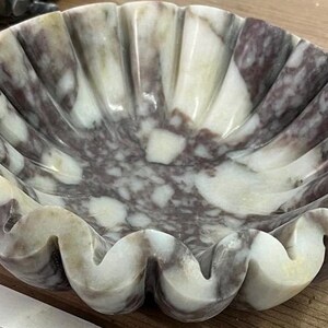 Pu&ograve; includere: Una ciotola decorativa in marmo con bordo smerlato. La ciotola presenta un mix di tonalit&agrave; bianche, grigie e viola. Il design della ciotola ricorda una conchiglia. Questa ciotola &egrave; adatta per scopi decorativi.