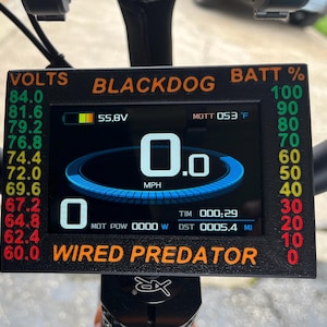 May include: A rectangular digital display screen labeled BLACKDOG and WIRED PREDATOR in orange text. The screen shows a speedometer at 0.0 MPH, a battery icon at 55.8V, motor temperature at 53 degrees Fahrenheit, and a distance of 0005.4 miles.