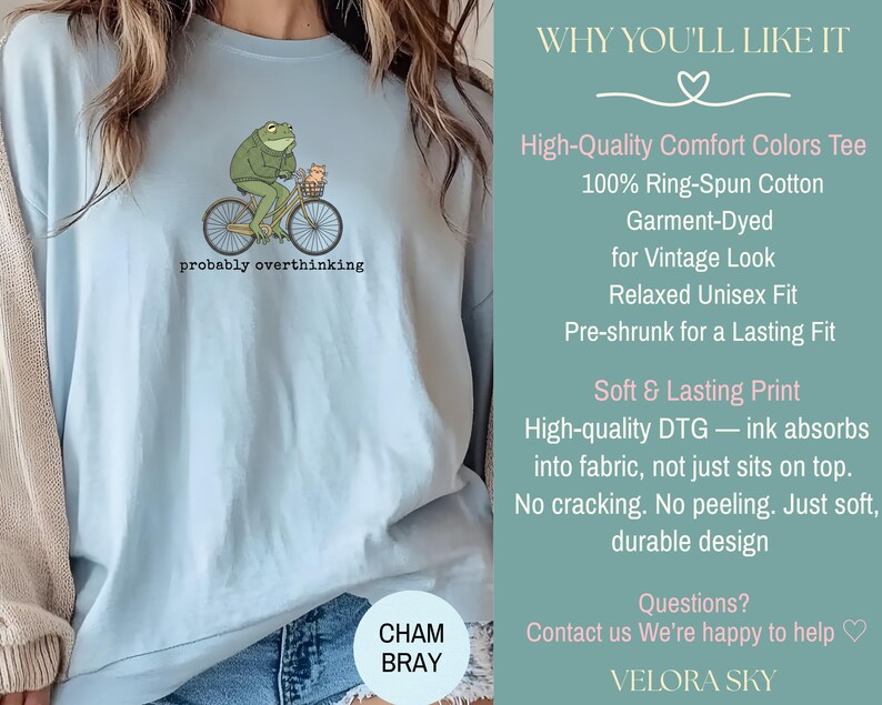 May include: Light blue t-shirt featuring a green frog riding a bicycle with a basket. The frog is wearing a hat and the text "probably overthinking" is below the graphic. The shirt is made of 100% ring-spun cotton.