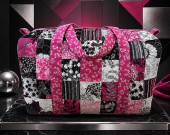 May include: A rectangular quilted duffel bag featuring a patchwork design of squares in shades of hot pink, black, white, and gray. The bag has two matching pink fabric handles and a zippered top closure with a repeating floral and botanical pattern.