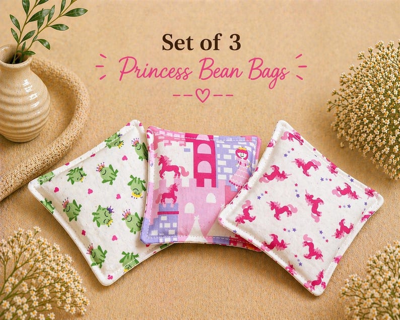 May include: A set of three square bean bags featuring fabric prints of green frogs with crowns, a pink castle with a princess and unicorns, and pink unicorns with stars. The text Set of 3 Princess Bean Bags is printed above the items.