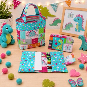 May include: A fabric tote bag, a rectangular zippered pouch, and a folding crayon roll featuring a colorful dinosaur and butterfly pattern. The items are made of quilted cotton fabric in shades of teal, pink, and orange with polka dot accents.