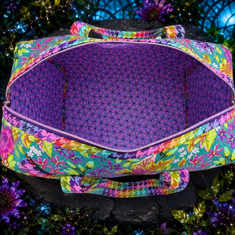 May include: A quilted duffel bag featuring a vibrant floral pattern in shades of teal, pink, and yellow with a houndstooth trim. The interior is lined with a purple fabric covered in a small black polka dot pattern and a zipper closure.