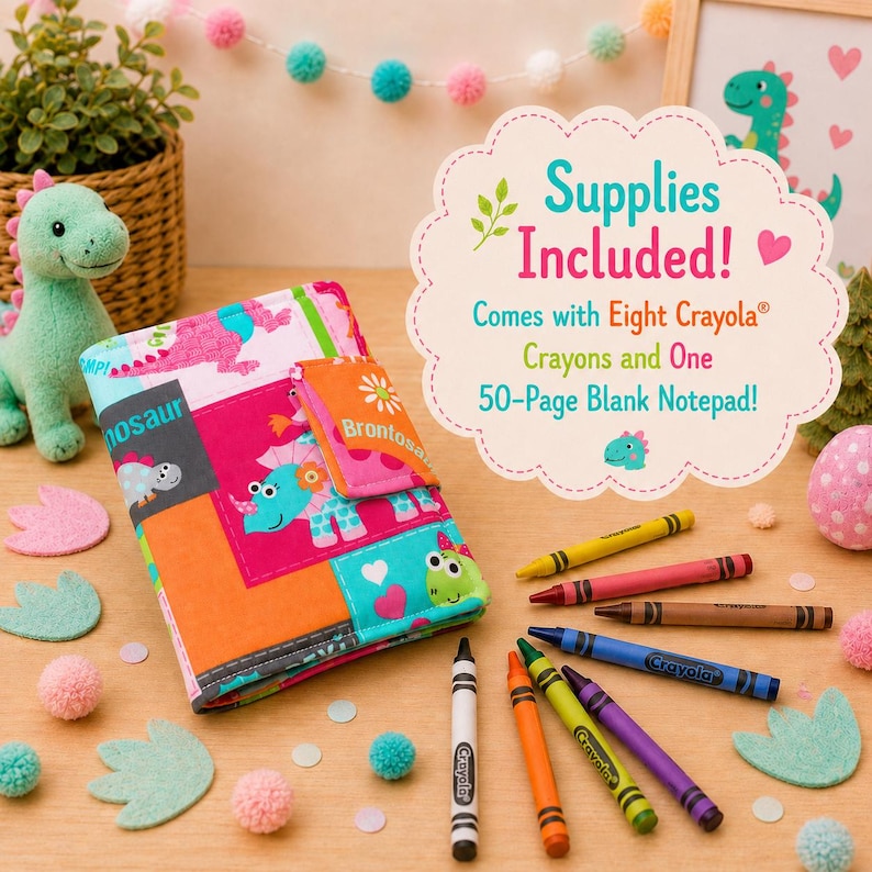 May include: A fabric notebook cover featuring a colorful dinosaur print in shades of pink, orange, and teal. The cover includes a flap closure and is accompanied by eight Crayola crayons. Text on the included sign reads: Supplies Included! Comes with Eight Crayola Crayons and One 50-Page Blank Notepad!