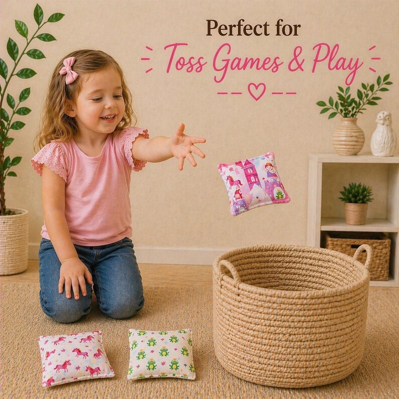 May include: A round, woven tan rope basket with two handles, accompanied by three small square fabric bean bags featuring colorful patterns of unicorns, frogs, and a castle, with the text Perfect for Toss Games & Play visible above.