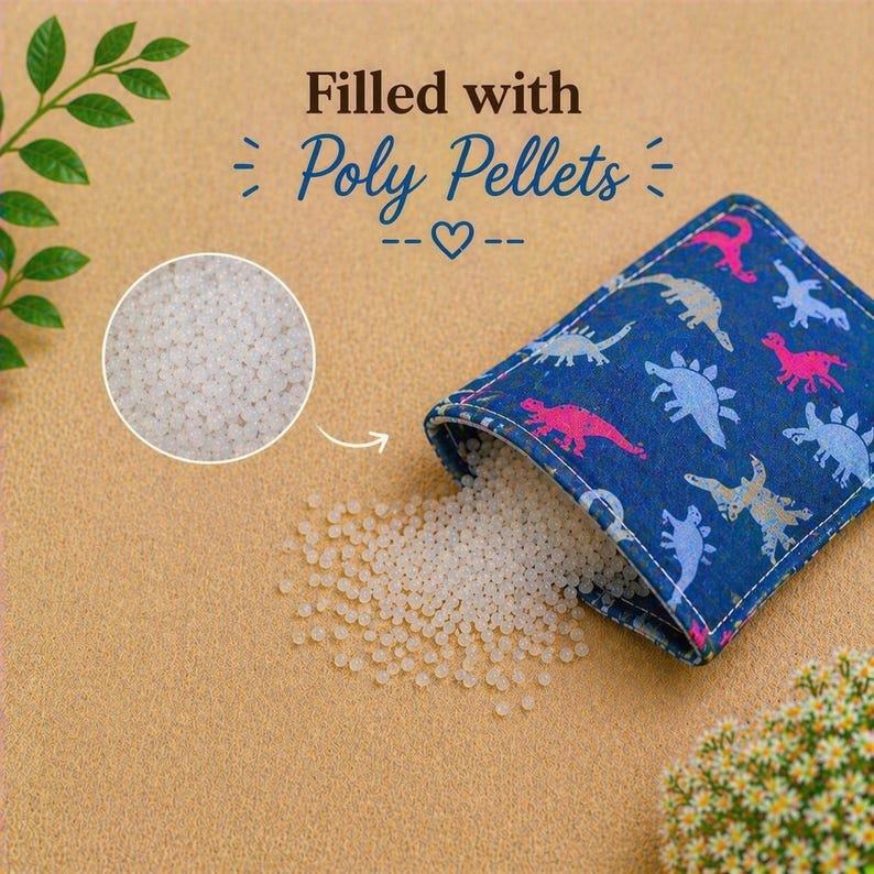 May include: A blue fabric pouch featuring a repeating pattern of pink and light blue dinosaurs. The pouch is partially open, spilling small white poly pellets onto the surface. Text above reads: Filled with Poly Pellets with a heart icon.
