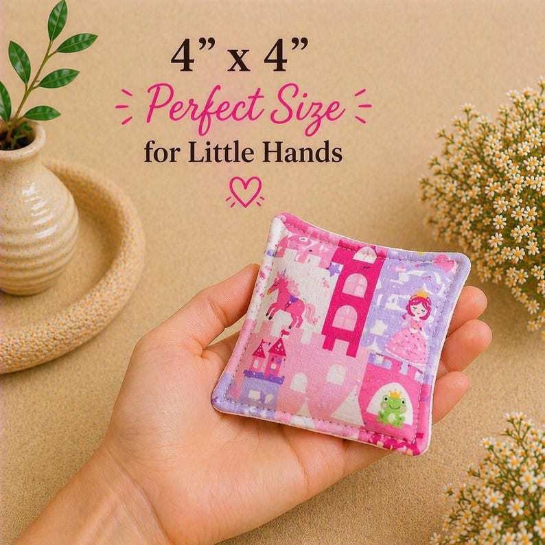 May include: A square fabric bean bag measuring 4 inches by 4 inches, featuring a pink and purple pattern with a unicorn, a castle, a princess, and a frog. The text 4 x 4 Perfect Size for Little Hands is printed above the object.