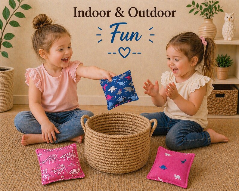 May include: A set of three square fabric bean bags featuring dinosaur patterns in blue and pink, accompanied by a round woven jute basket. The text "Indoor & Outdoor Fun" is displayed above the items in a decorative font style.